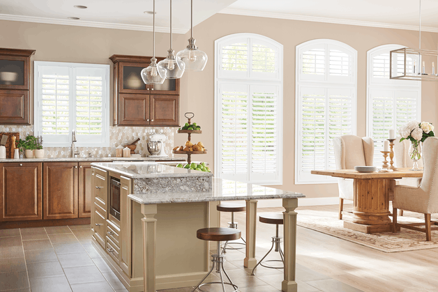 White hinged plantation shutters in a sunlit dining room, offering a polished, traditional finish with flexible light and privacy control