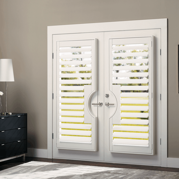 White hinged plantation shutters on French doors, combining functional light control with an elegant, seamless door treatment