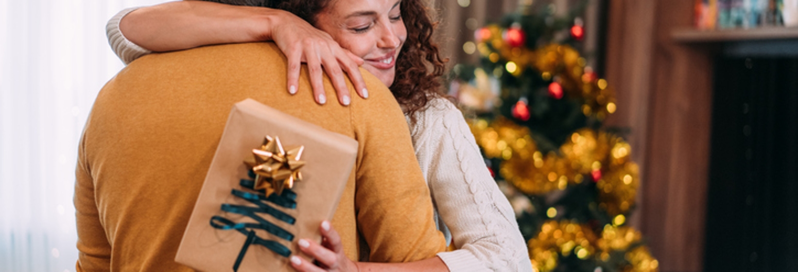 Husband hugging wife after giving a Christmas gift | Gotcha Covered