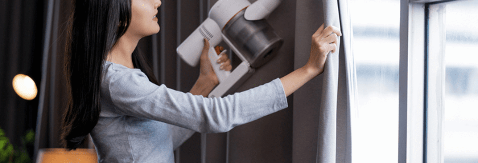 Close-up of woman cleaning curtains and small vacuum | Gotcha Covered