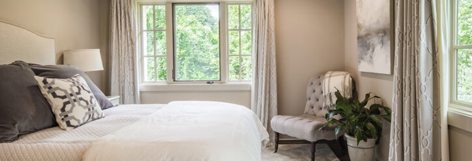 Floor-to-ceiling drapes in a master bedroom, providing full light control and privacy alongside a neatly made bed