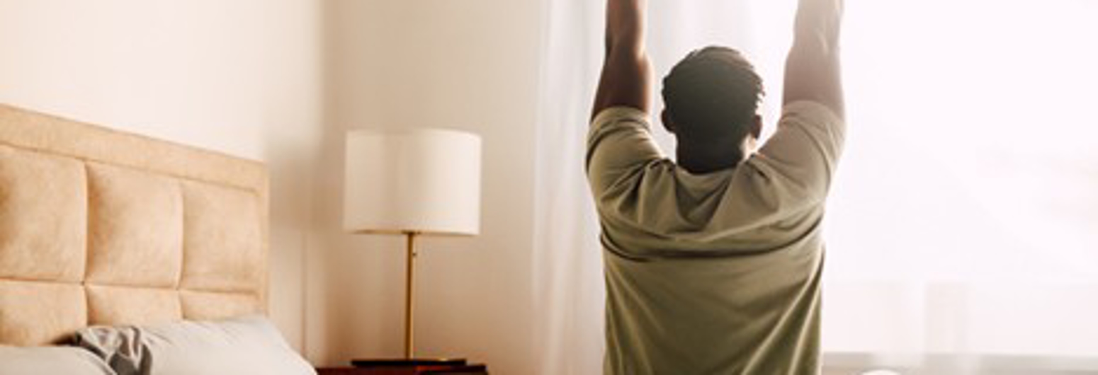African American man sitting on bed and stretching | Gotcha Covered
